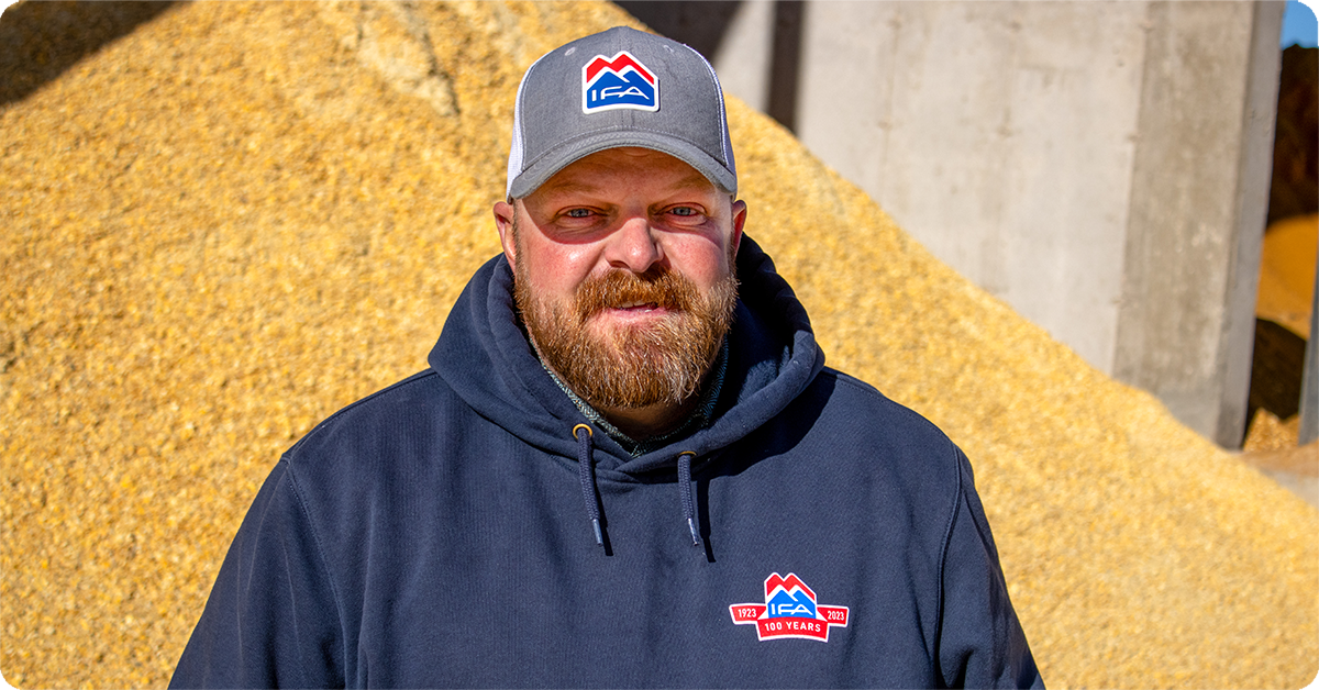 Wayne Brinkerhoff poses in front of a large pile of grain.