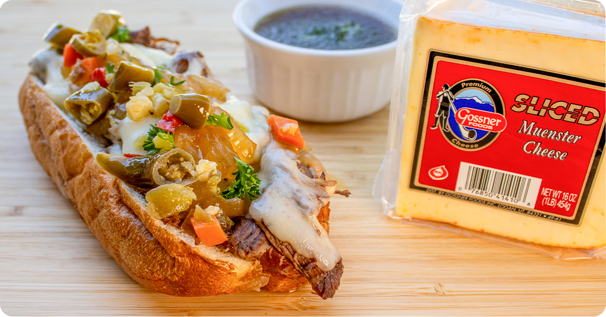 A delicious Cheesy Chuck Roas Sandwhich topped with muenster cheese and vegetables.