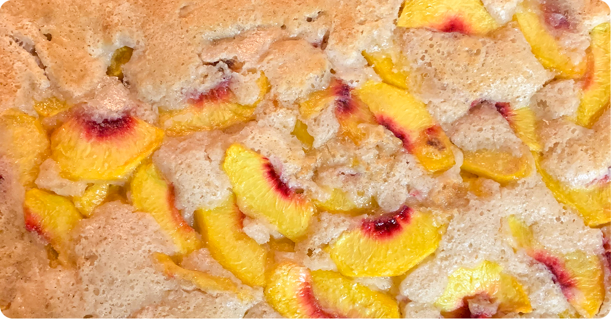 A close up photo of fresh peaches baked into a buttery sweet cobbler.